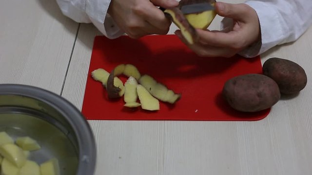 Woman hands peeling of poteto.