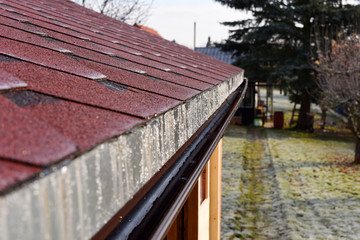 Modern roof shingles tiles. Soft asphalt roof cover and roofing construction for a small house in the garden. Easy roofing repair. Czech republic, Europe.