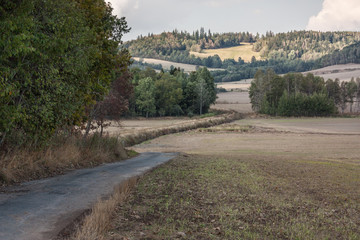 Late summer landscape in the picturesque Kaczawskie Mountains. Cultivated fields after the harvest. Deep dark green trees, earth in shades of brown, straw yellow Poland, Lower Silesia.