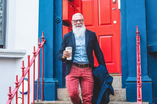 Senior Hipster Man Going Out From Home While Drinking Coffee At Morning Time - Trendy Lifestyle,  And Joyful Elderly Lifestyle Concept - Focus On Face