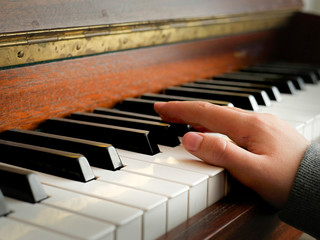 Teenager hand on piano keys, grey sleeves , Concept music practice, training, developing fluent hand movement.