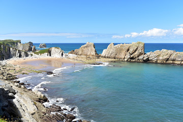 Tourists enjoying the sun in the beach of Playa De La Arnia on a sunny day, Santander. Cantabria, Spain