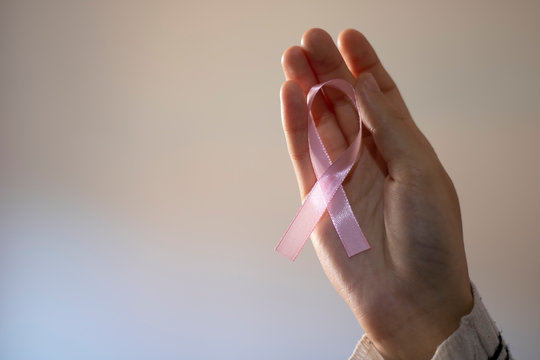 Woman Taking A Pink Ribbon In Tribute To Breast Cancer Patients.