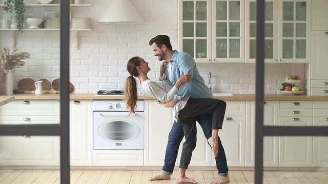 Happy romantic young couple husband and wife dancing in kitchen