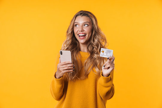 Image of young blonde woman holding credit card and cellphone
