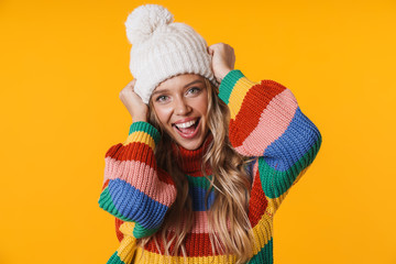 Image of delighted young woman in winter hat and sweater smiling at camera