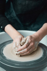 Woman making ceramic pottery on wheel, hands close-up, creation of ceramic ware. Handwork, craft, manual labor, buisness. Earn extra money, turning hobbies into cash and passion into job, vertical