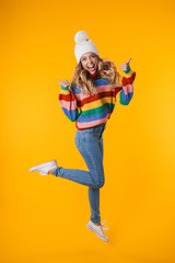 Full length image of blonde woman in winter hat showing thumbs up