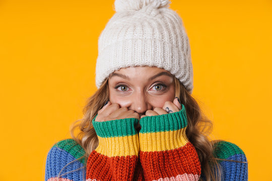 Image of frozen blonde woman in winter hat staying warm in her sweater