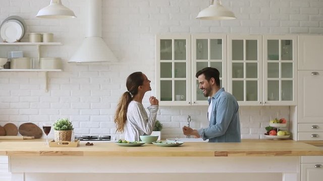 Young happy active family couple dancing laughing together in kitchen