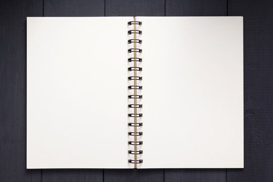 notepad or notebook paper at black wooden background