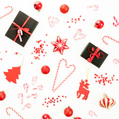Christmas winter composition. Gift box, red decoration, candy canes and confetti on white. Flat lay