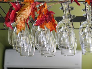 Crystal-clear wine glasses hanging from a wine rack at a bar