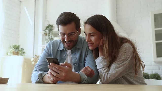 Happy couple using smartphone play mobile game shopping in app