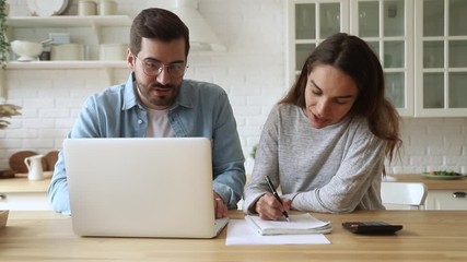 Young couple doing paperwork using laptop sit at kitchen table - Powered by Adobe