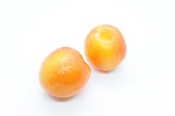 Orange wet tasty plums located on a white background