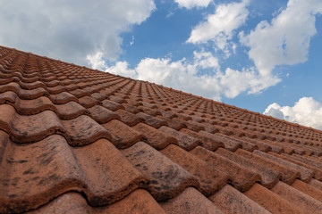 roof top on sky background. Close up of brown clay roof tiles. Red old dirty roof. Old roof tiles. Construction equipment build a house.