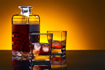 Whiskey with ice on a black reflective background