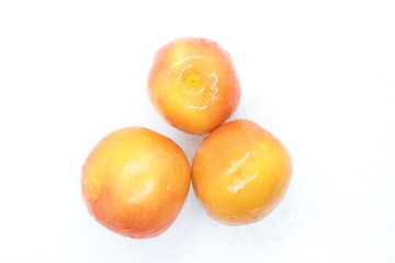 Orange wet tasty plums located on a white background