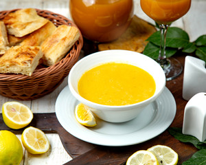 lentil soup in a white bowl and a slice of lemon