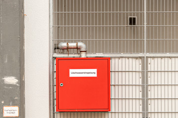 Hydranten mit Rohren an einer Wand in rot mit Aufschrift in deutschen Löschwassereinspeisung