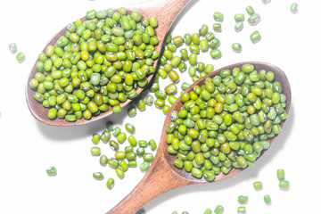 Wooden spoons of mung beans on a white background