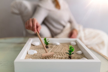 Hand of beautiful young woman using her Zen garden at home. Lovely young smiling woman relaxing with her Zen garden and enjoying her day