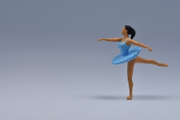 Tiny ballerina dancer in blue dress standing on one leg