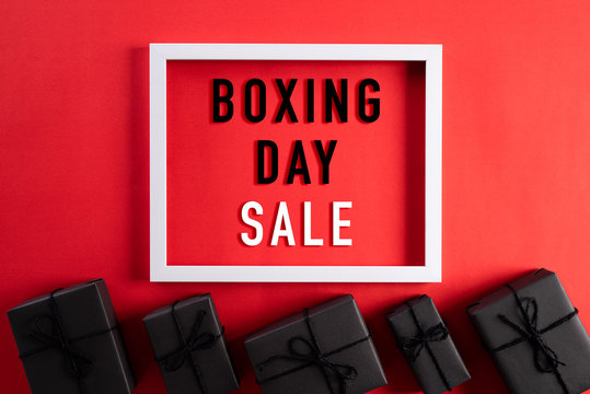 Top view of Black Friday Sale text on white picture frame with black gift box red background. Shopping concept and Boxing day composition.
