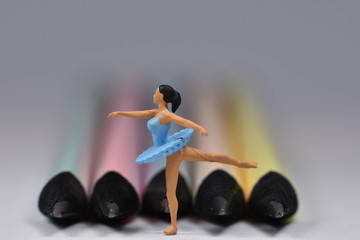 Tiny ballerina dancer in blue dress standing on one leg