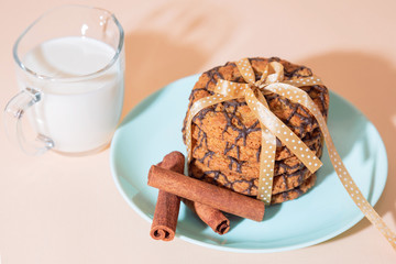 Healthy vegetarian cereal oats food, sweet dessert, snacks, culinary products. Oatmeal cookies with chocolate, cinnamon, milk. Breakfast on a blue turquoise plate on a background of peach pastel color