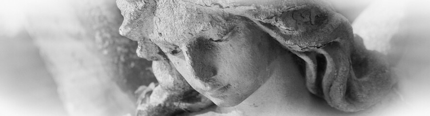 Fragment of ancient statue of sad angel. Close up yeges of angel. Death, pain and end of life concept.