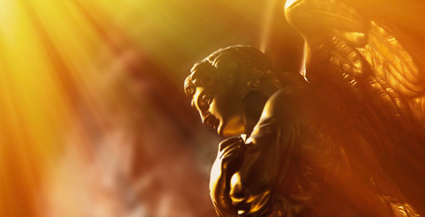 Gold angel in the sunlight. Antique statue.