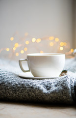 Cup of coffee with milk on cozy knitted winter blanket