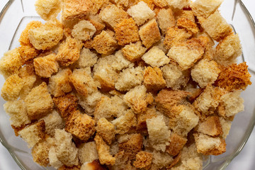 Crackers or croutons of homemade white bread close-up in a glass plate. Texture of slices of dry rye bread.