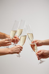 cropped view of men and women toasting champagne glasses with sparkling wine isolated on grey © LIGHTFIELD STUDIOS