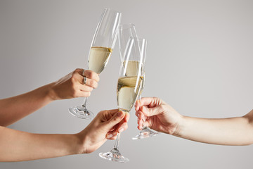 cropped view of women toasting champagne glasses with sparkling wine isolated on grey