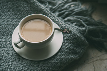 Cup of coffee with milk on cozy knitted winter blanket