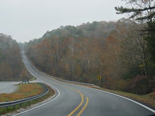 Scenic road with colorful trees and foliage on a rainy autumn morning in Arkansas, USA.