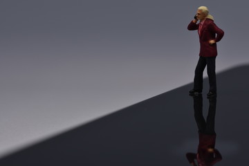 miniature man standing on a phone talking with a smartphone
