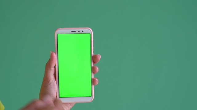 Closeup view of female hands holding smartphone with empty blank green screen. Woman browsing virtual and invisible pages of webside using touchscreen. Real time 4k video footage.