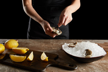 cropped view of woman holding fork near oyster isolated on black