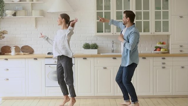 Happy funky young romantic couple dancing jumping in kitchen