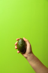 avocado in a hand of woman green background. healthy food concept