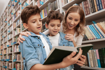 Lovely family looking excited and overwhelmed, reading a book at the library. Twin brothers and...