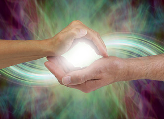 Together our energy is stronger - female hand cupped over a male cupped hand with a bright white...