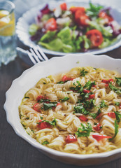 instant noodles in white bowl on wooden table background and vegetables salad on plate