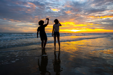 Black silhouettes of couple girl against the sunset on the sea.