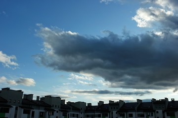 Big dark clouds lit by the rays of the sun, are floating in the blue sky
