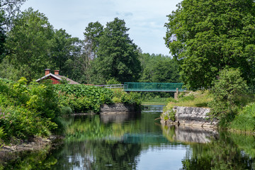 Fototapeta na wymiar Beautiful canal with lush green vegetation in summer sunlight